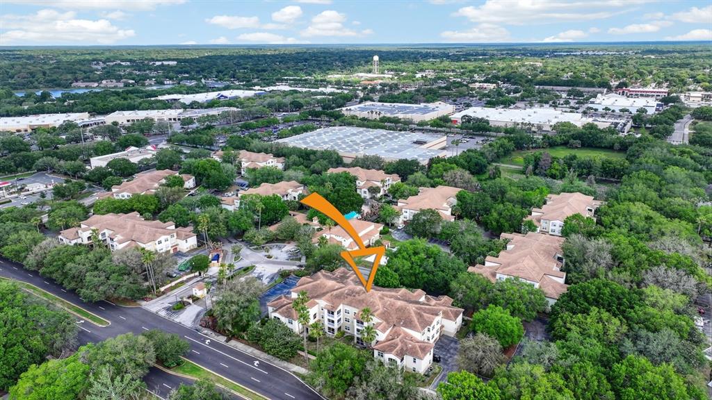 An aerial view shows a multi-story apartment building with a brown roof surrounded by trees — 832 CAMARGO WAY UNIT 306, ALTAMONTE SPRINGS, FL