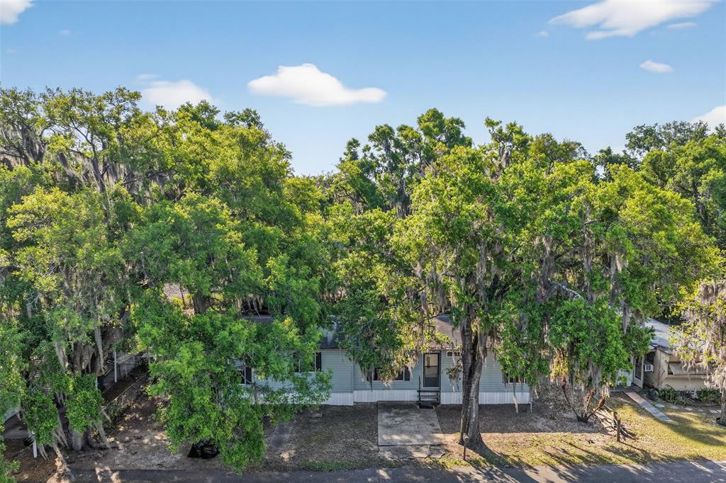 A single-story manufactured home is nestled among large, moss-draped oak trees — 904 MAPLEWOOD STREET, TAVARES, FL