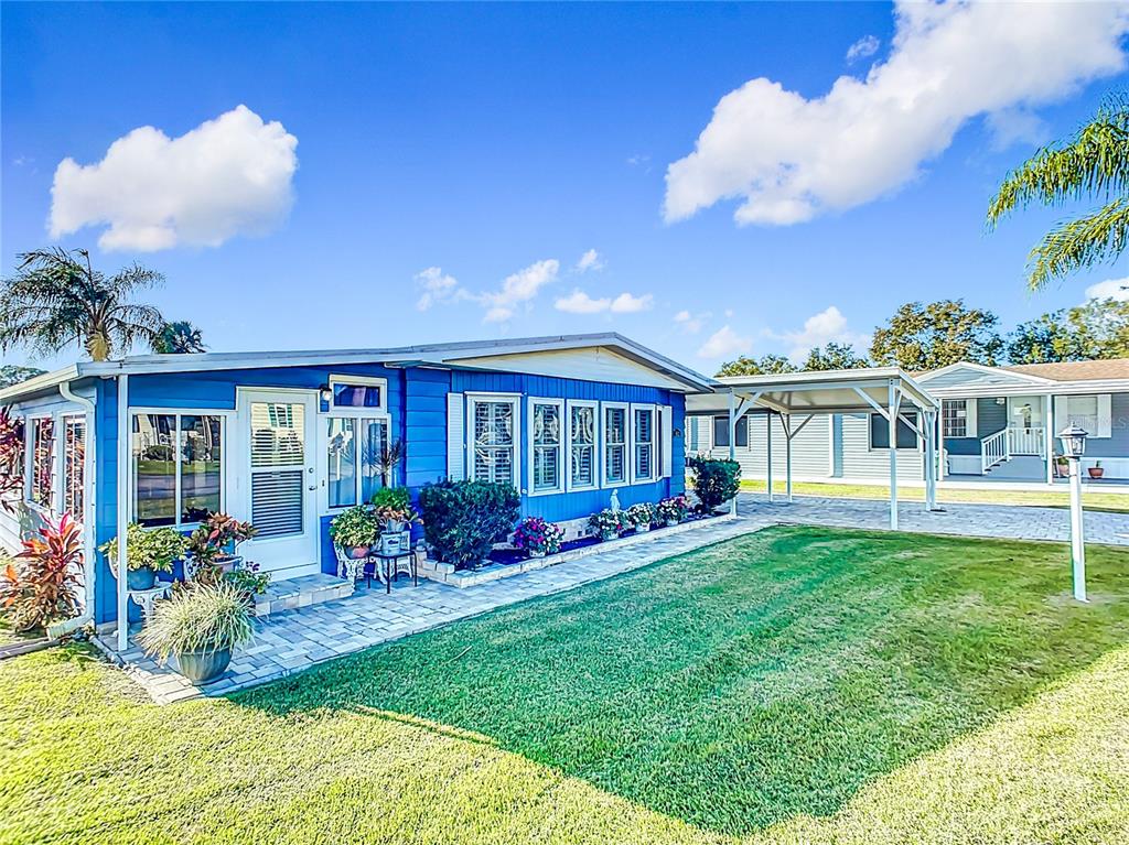 A blue mobile home with a paved walkway, a carport, and a green lawn — 812 SWALLOW LANE, OSTEEN, FL