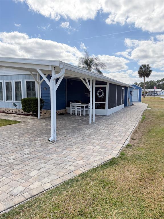 A blue mobile home features a paved driveway, a white carport, and a screened-in porch — 812 SWALLOW LANE, OSTEEN, FL