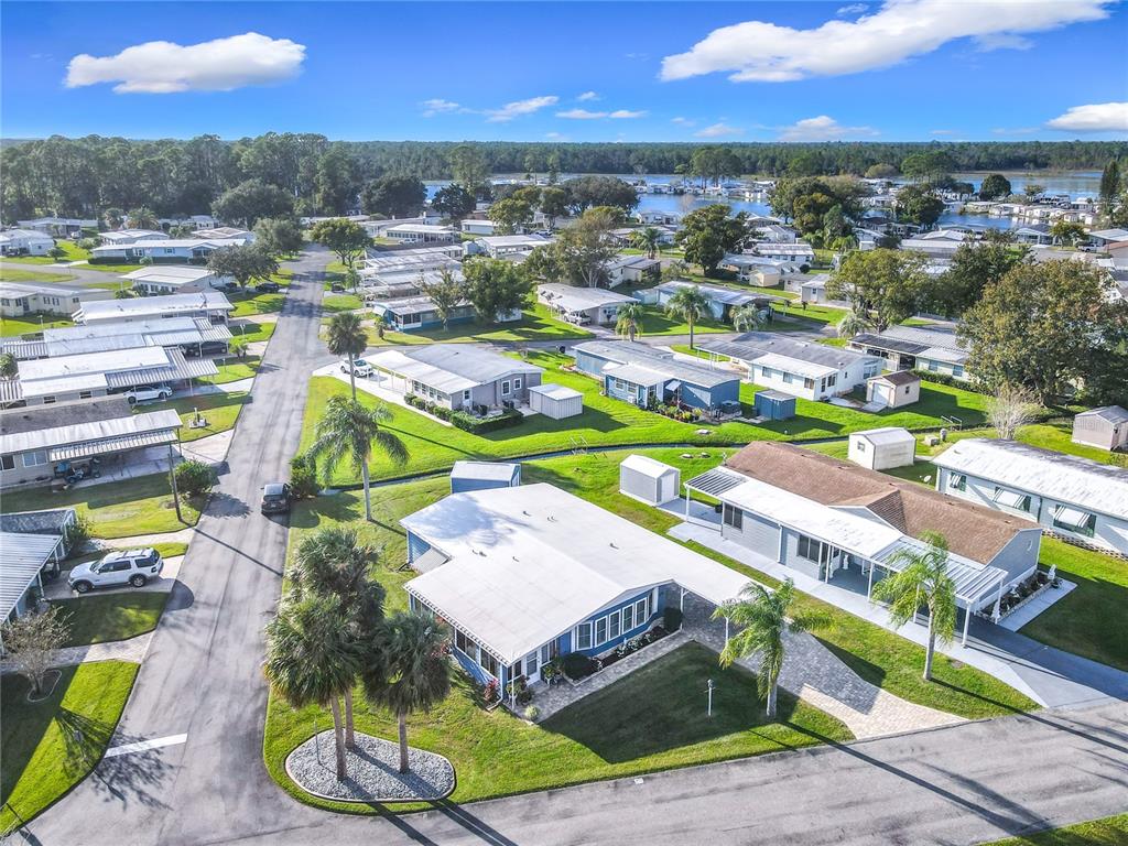 An aerial view shows a residential neighborhood of manufactured homes with palm trees and streets — 812 SWALLOW LANE, OSTEEN, FL