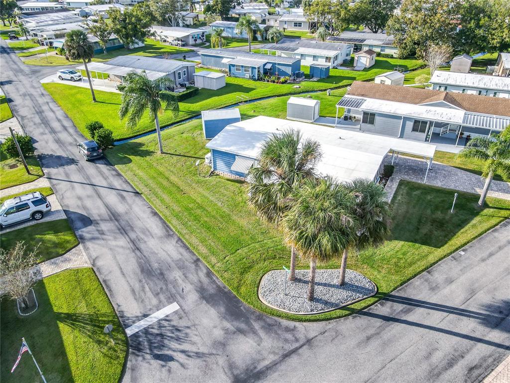 An aerial view shows a blue mobile home with a white roof and palm trees — 812 SWALLOW LANE, OSTEEN, FL