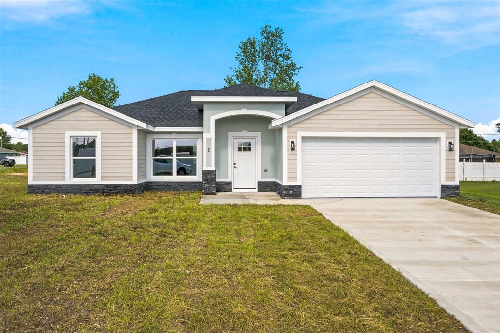 A single-story house with light-colored siding, a dark roof, and a two-car garage — 1 DOGWOOD DRIVE PASS, OCALA, FL