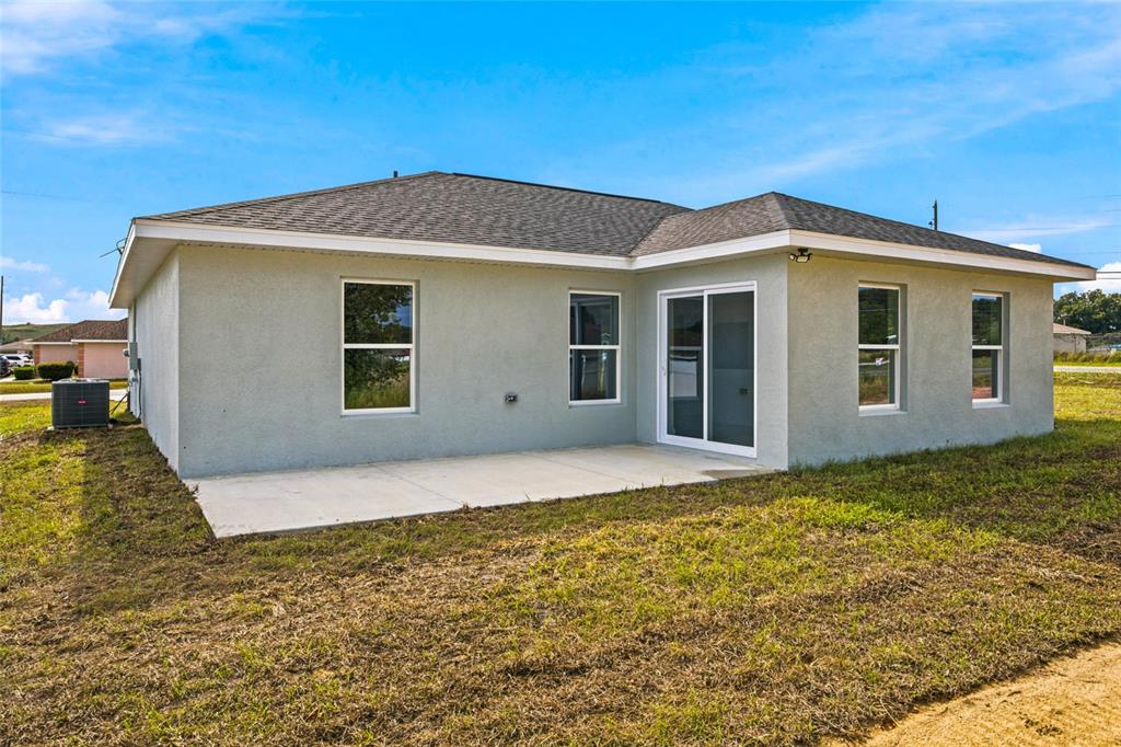 The rear exterior of a single-story house features a concrete patio and sliding glass doors — 1 DOGWOOD DRIVE PASS, OCALA, FL