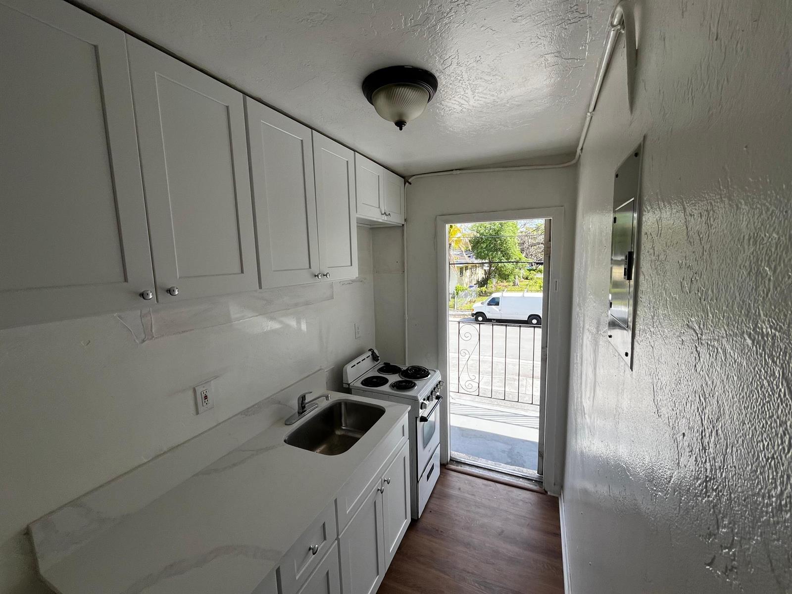 A small kitchen features white cabinets, a stainless steel sink, and an electric stove — 3015 NW 8th Avenue # 9, Miami FL 33127, MIAMI, FL