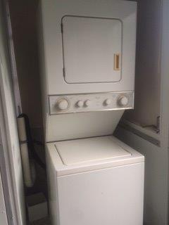 A white stacked washer and dryer unit is installed in a small laundry closet — 482 Monaco K # 482, Delray Beach FL 33446, DELRAY BEACH, FL