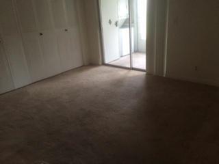 A bedroom with beige carpet, white closet doors, and a sliding glass door to a balcony — 482 Monaco K # 482, Delray Beach FL 33446, DELRAY BEACH, FL
