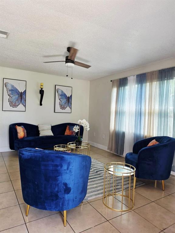 A living room features blue velvet furniture, butterfly wall art, and a ceiling fan — 2316 MISPAH AVENUE, LEESBURG, FL