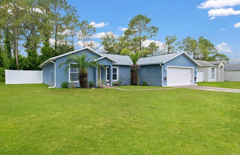 A blue single-story house with a two-car garage and two palm trees in the front yard — 54 PENNSYLVANIA LANE, PALM COAST, FL
