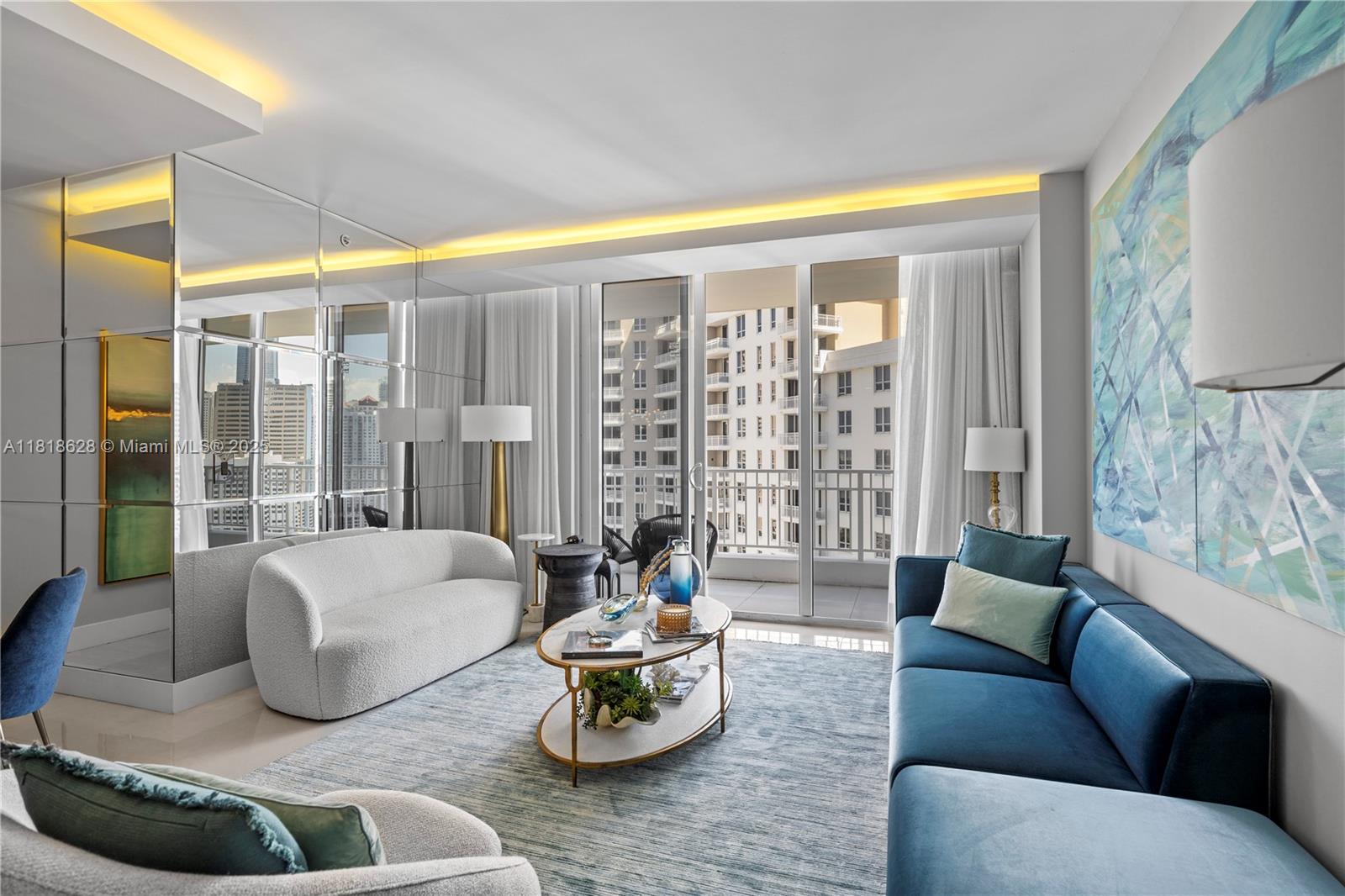 A modern living room features a blue sofa, a white curved sofa, and mirrored walls — 801 Brickell Key Blvd # 2203, Miami FL 33131, MIAMI, FL