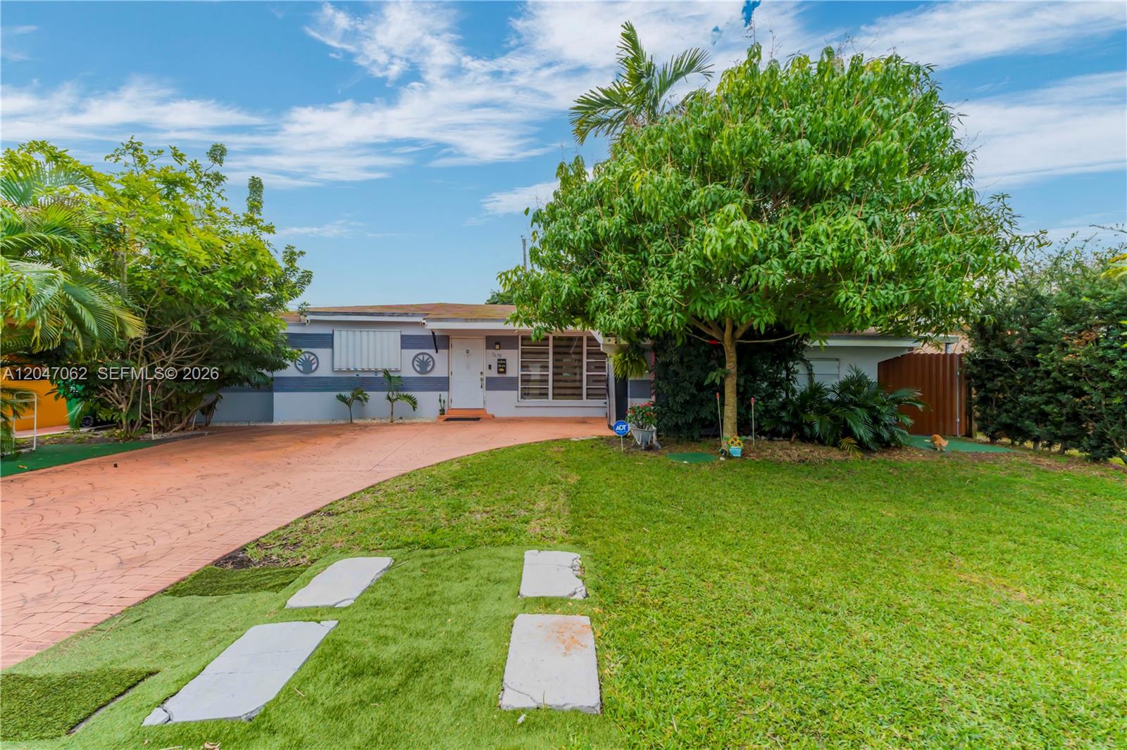 A single-story house features a stamped concrete driveway, a large tree, and a grassy lawn — 7630 Plantation Blvd, Miramar FL 33023, MIRAMAR, FL