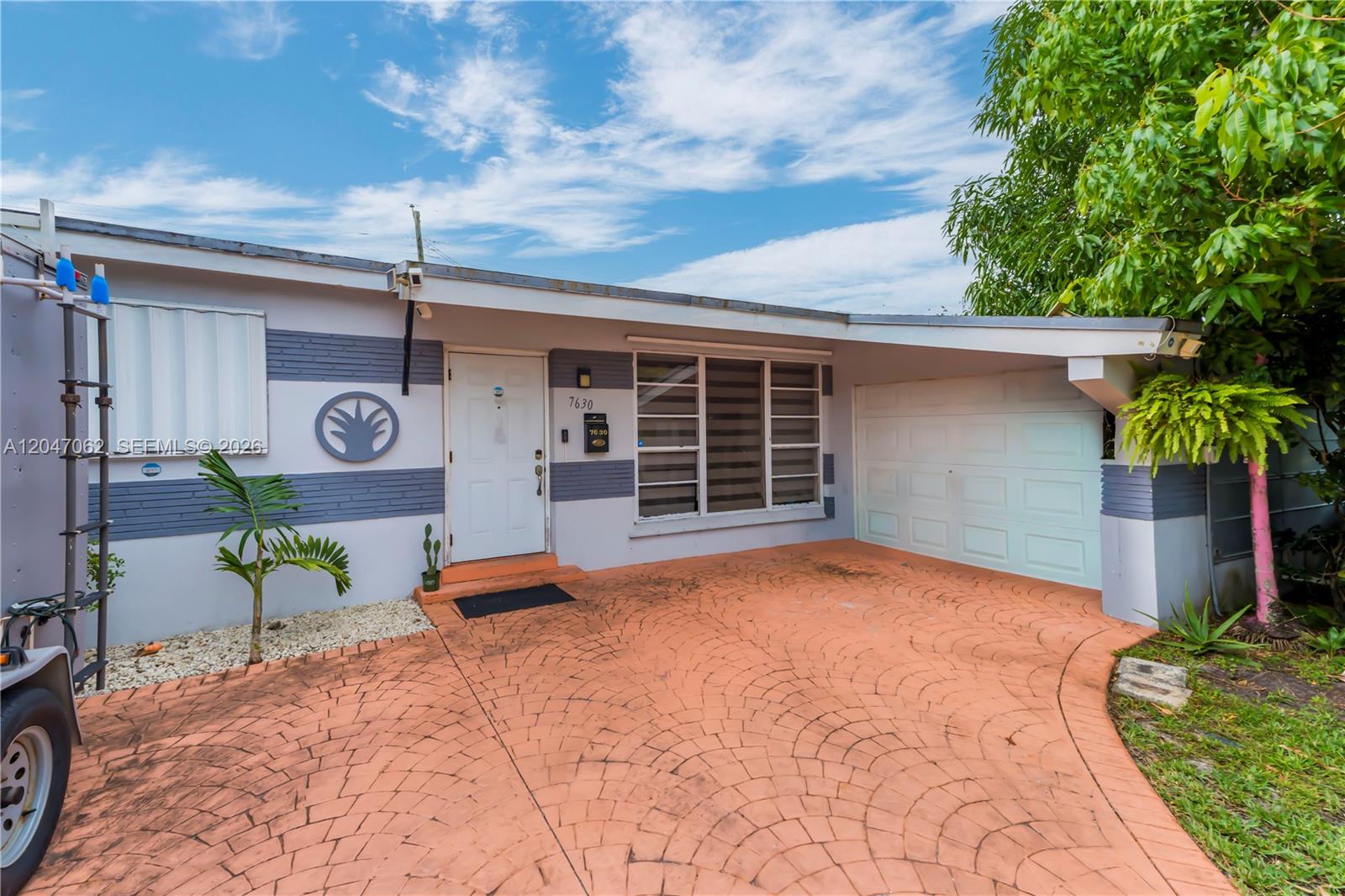 The exterior of a single-story house features a patterned driveway, a carport, and a white door — 7630 Plantation Blvd, Miramar FL 33023, MIRAMAR, FL
