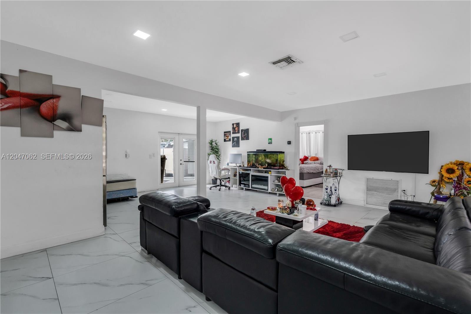 A living room features white tile floors, black leather sofas, and a large fish tank — 7630 Plantation Blvd, Miramar FL 33023, MIRAMAR, FL