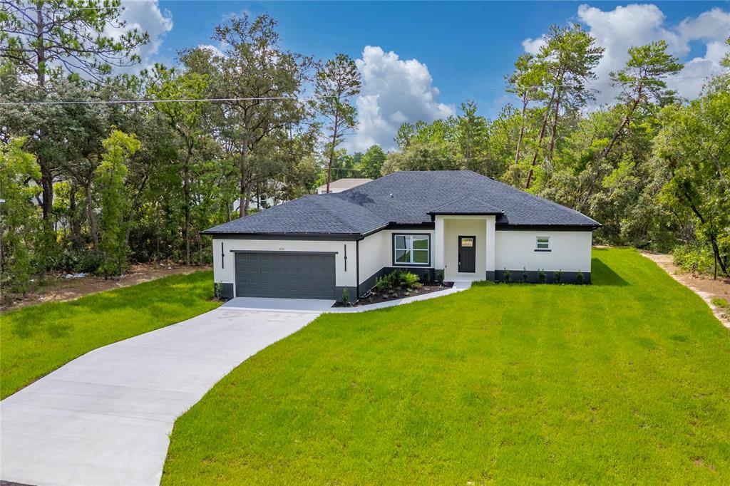 A single-story house with a dark roof, white stucco walls, and an attached garage — 455 MARION OAKS PASS, OCALA, FL
