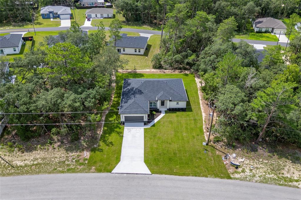 An aerial view shows a single-story house with a dark roof and a concrete driveway — 455 MARION OAKS PASS, OCALA, FL
