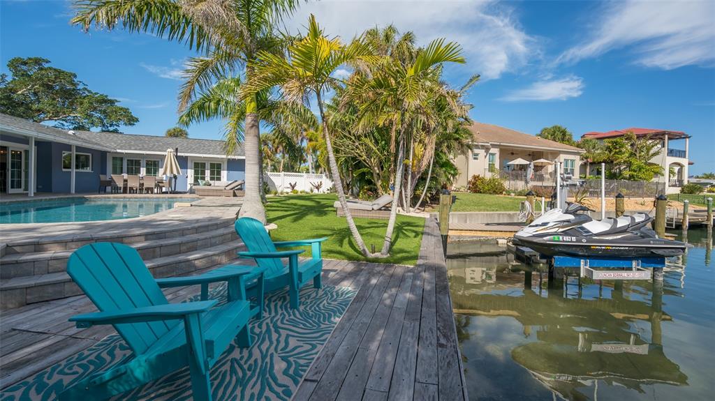 A backyard patio with turquoise chairs, a swimming pool, and a jet ski on a lift — 500 SCHOONER LANE, LONGBOAT KEY, FL
