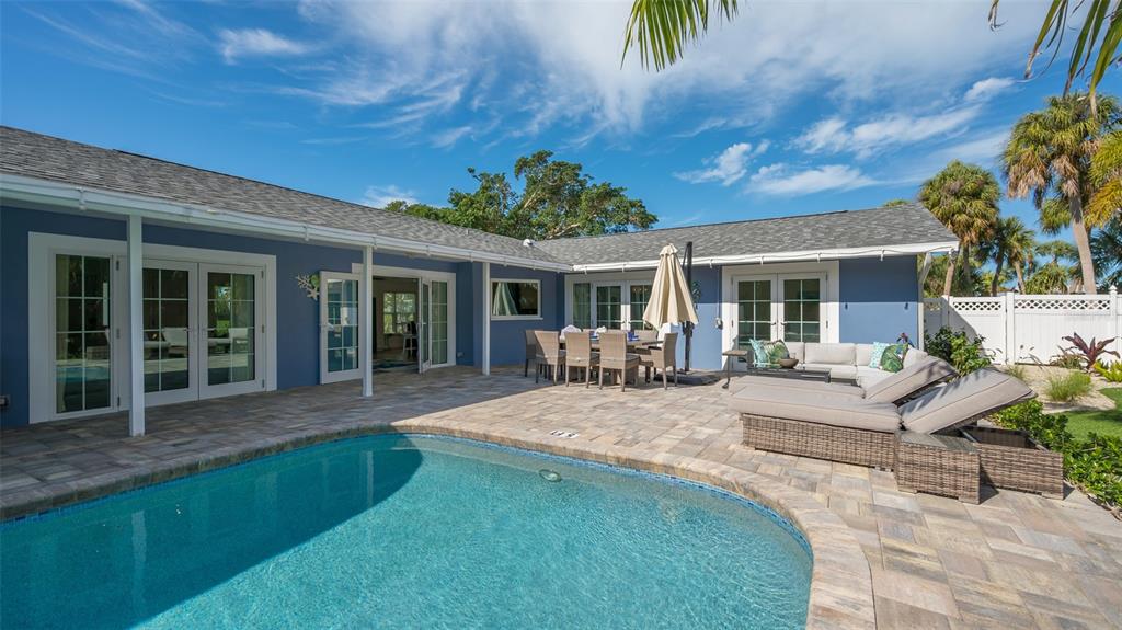 A blue house with a patio, swimming pool, outdoor dining set, and lounge chairs — 500 SCHOONER LANE, LONGBOAT KEY, FL