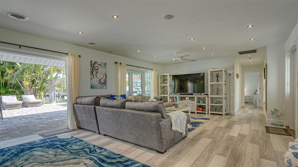A living room features gray sectional seating, a television console, and sliding doors opening to a patio — 500 SCHOONER LANE, LONGBOAT KEY, FL