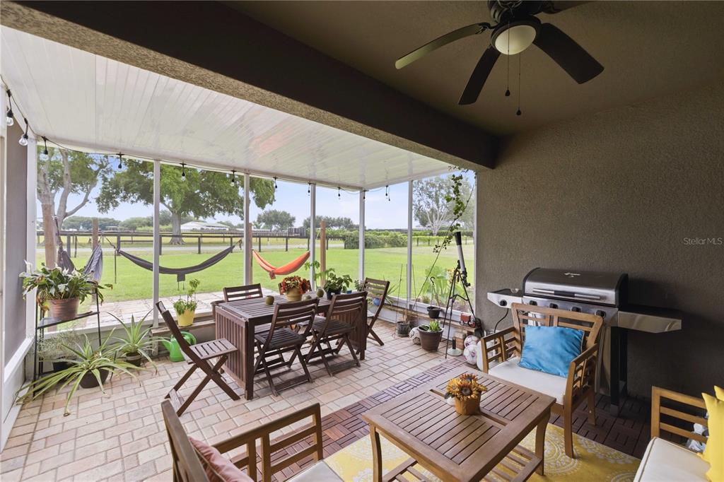 A covered patio features a dining set, lounge seating, a grill, and a screened-in view — 6824 SW 64TH TERRACE, OCALA, FL