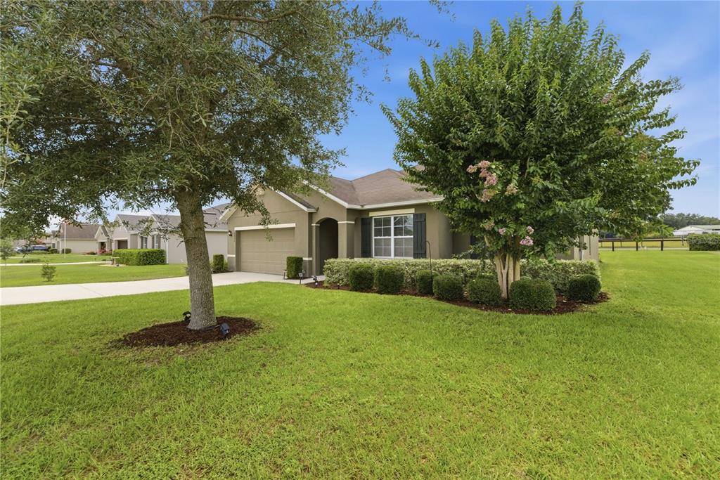 A single-story house with a tan exterior, a two-car garage, and a manicured front lawn — 6824 SW 64TH TERRACE, OCALA, FL