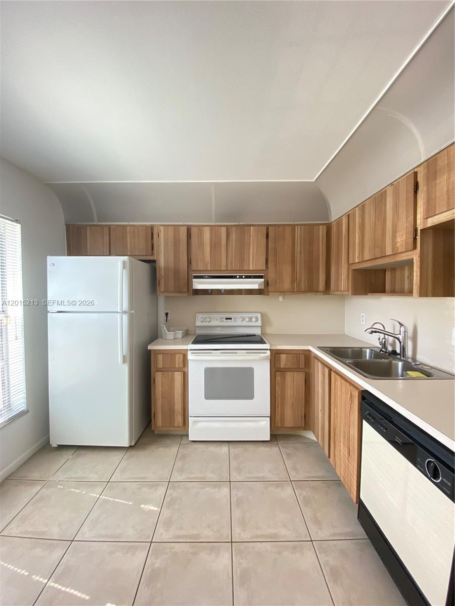 A kitchen features light wood cabinets, white appliances, beige tile flooring, and laminate countertops — 432 Bennington Ln # 432, Lake Worth FL 33467, LAKE WORTH, FL