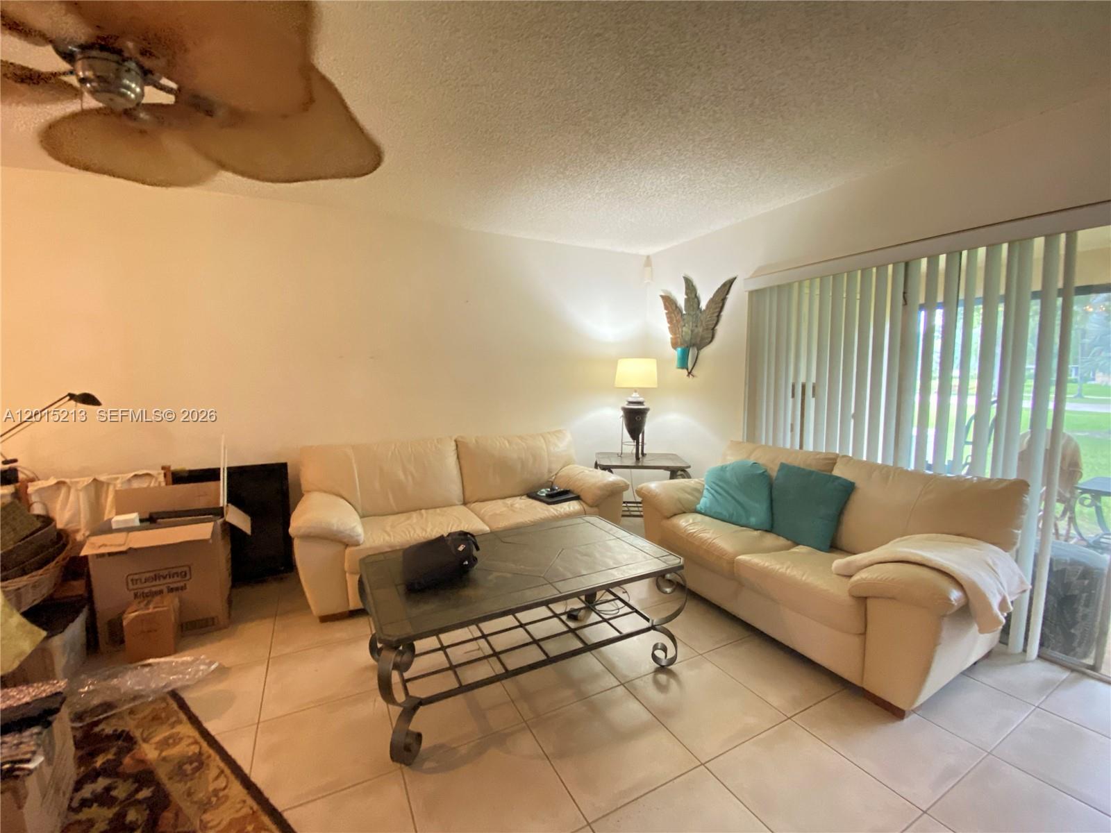 A living room features two cream-colored sofas, a metal coffee table, and tile flooring — 432 Bennington Ln # 432, Lake Worth FL 33467, LAKE WORTH, FL