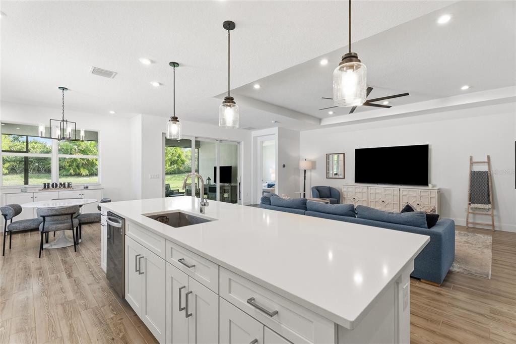A bright, open-concept kitchen and living area featuring a large white island and wood-look flooring — 11959 SW VIRIDIAN BOULEVARD, PORT ST LUCIE, FL