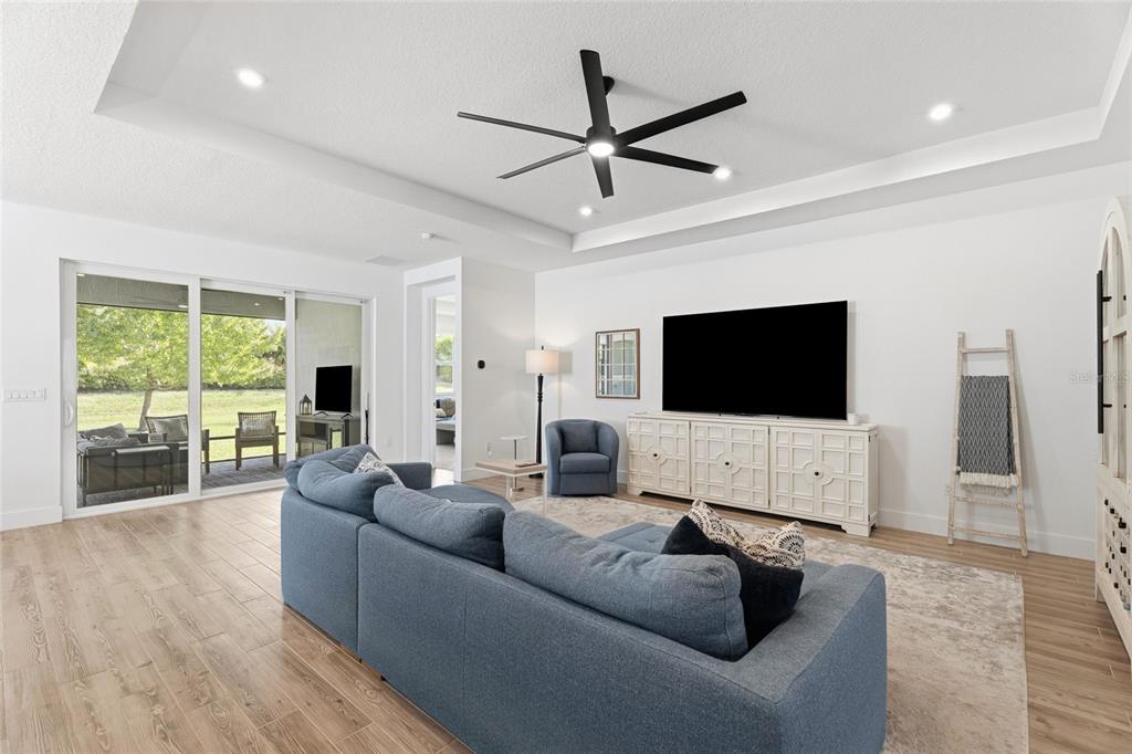 A living room features a blue sectional sofa, a large television, and a ceiling fan — 11959 SW VIRIDIAN BOULEVARD, PORT ST LUCIE, FL