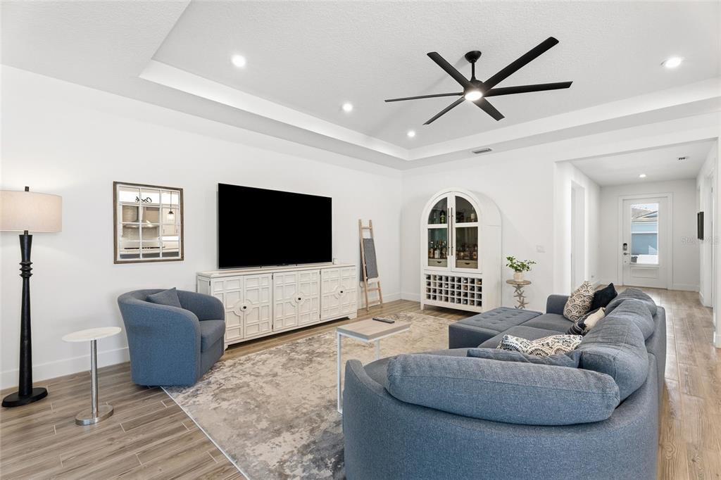 A living room features a tray ceiling, blue furniture, a television, and a white cabinet — 11959 SW VIRIDIAN BOULEVARD, PORT ST LUCIE, FL