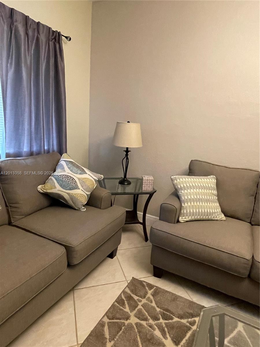 Two gray sofas face each other with a glass-topped side table and lamp between them — 10720 NW 66th St # 510, Doral FL 33178, DORAL, FL