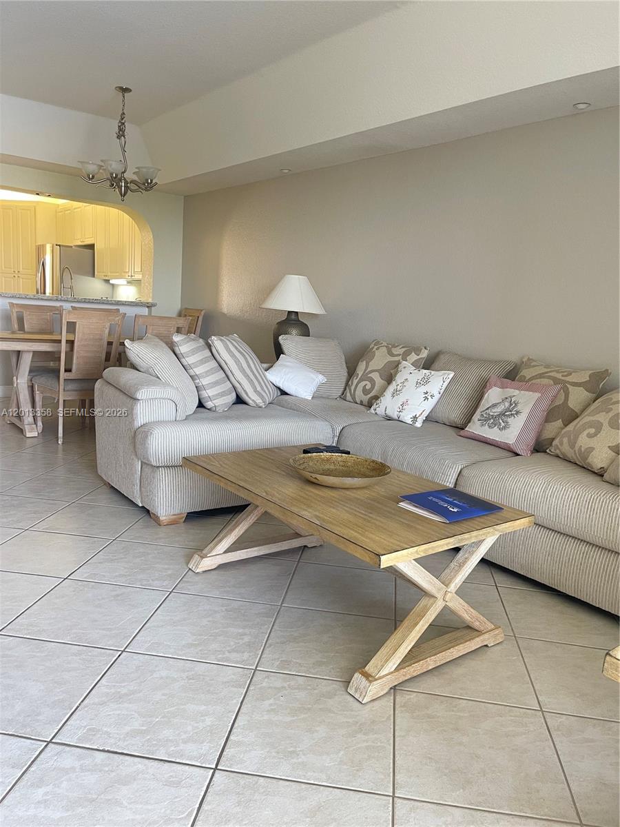 A living room features a large striped sectional sofa, a wooden coffee table, and tile flooring — 10720 NW 66th St # 510, Doral FL 33178, DORAL, FL