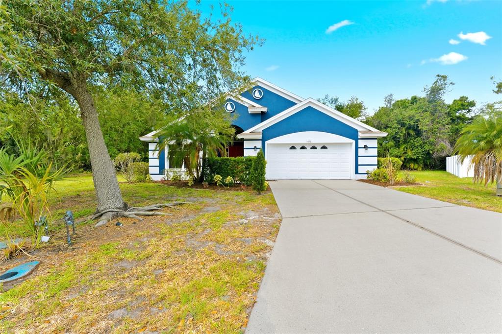 A blue single-story house with a white garage door and a concrete driveway — 5976 48TH STREET E, BRADENTON, FL