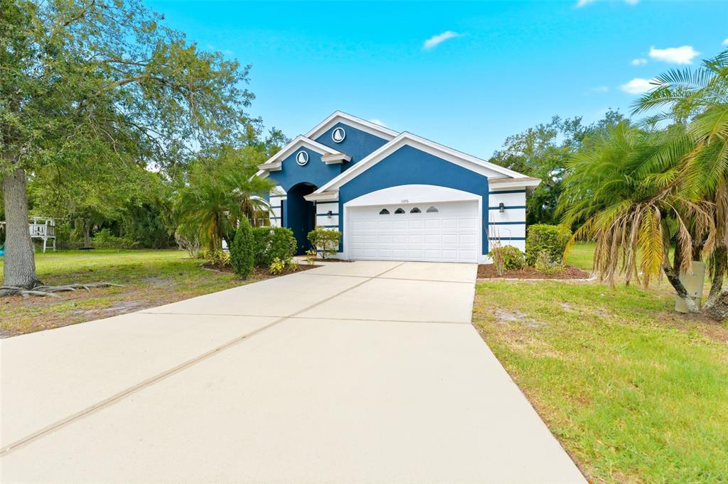 A blue single-story house with a white garage door and a concrete driveway — 5976 48TH STREET E, BRADENTON, FL