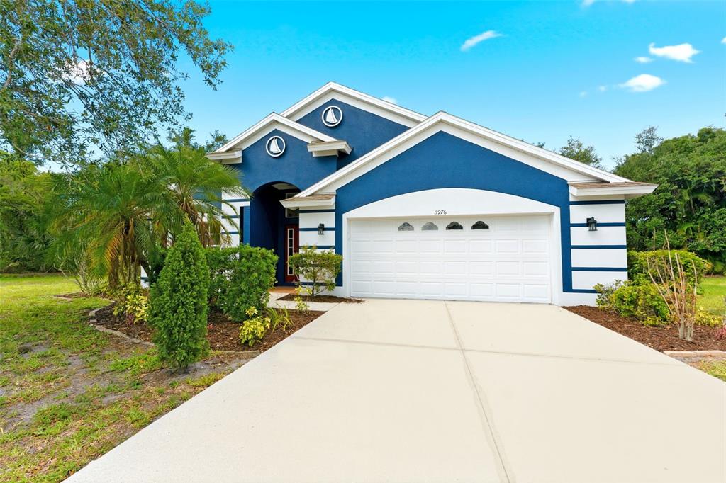A blue single-story house with a white garage door and a concrete driveway — 5976 48TH STREET E, BRADENTON, FL