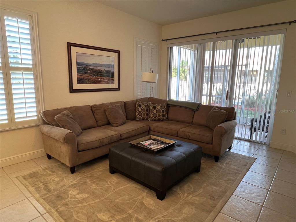 A living room features a brown sectional sofa, a leather ottoman, and a large sliding door — 240 W END DRIVE UNIT 611, PUNTA GORDA, FL