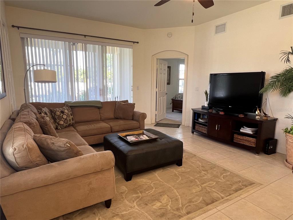 A living room features a tan sectional sofa, a dark ottoman, and a television console — 240 W END DRIVE UNIT 611, PUNTA GORDA, FL