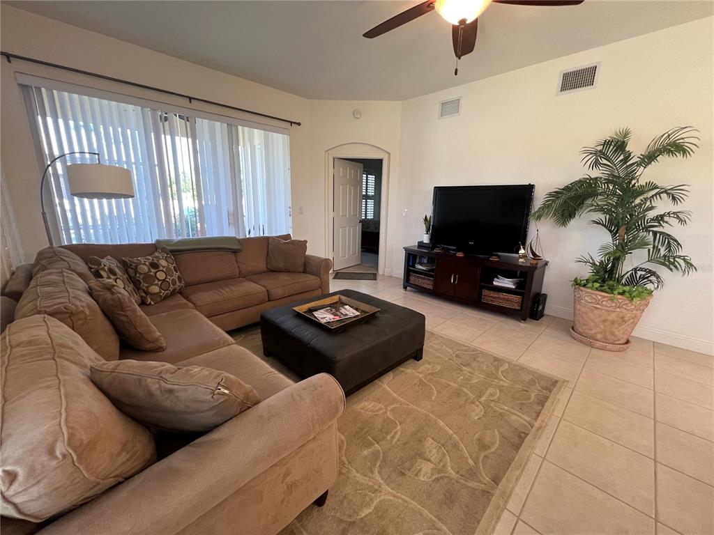 A living room features a brown sectional sofa, a black ottoman, and a television console — 240 W END DRIVE UNIT 611, PUNTA GORDA, FL