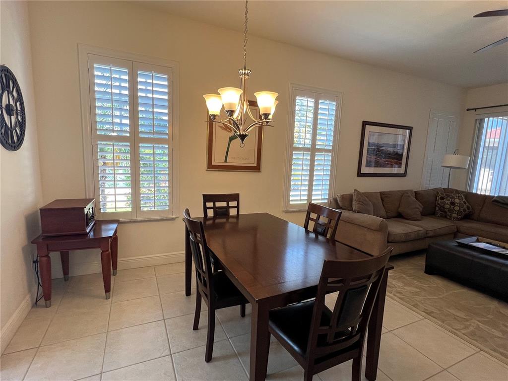 A dining area with a dark wood table and chairs sits beside a living room — 240 W END DRIVE UNIT 611, PUNTA GORDA, FL