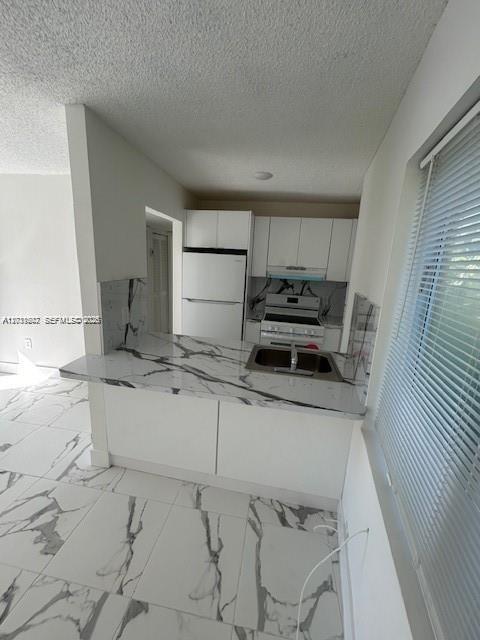 A kitchen features white cabinets, stainless steel appliances, and white marble-patterned countertops and flooring — 661 W 81st St # 4, Hialeah FL 33014, HIALEAH, FL