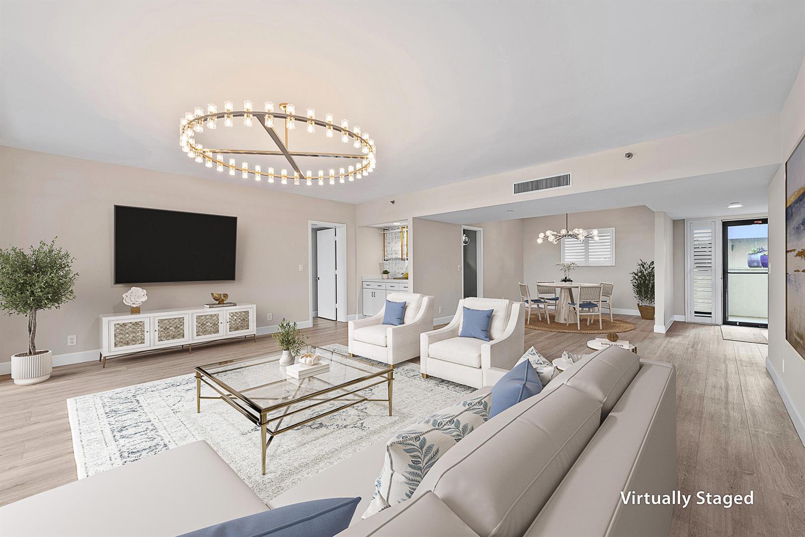 A living room with a large circular chandelier, glass coffee table, and adjacent dining area — 16910 Bay Street # E204, Jupiter FL 33477, JUPITER, FL