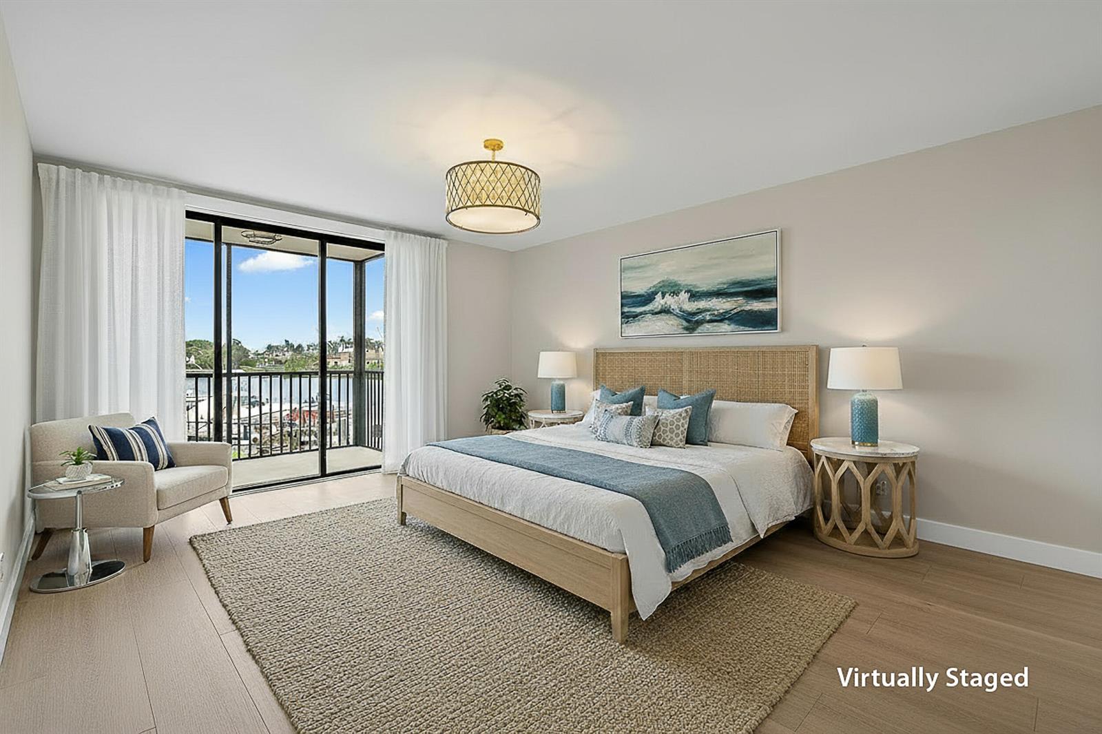A virtually staged bedroom features a king bed, a balcony with water views, and wood flooring — 16910 Bay Street # E204, Jupiter FL 33477, JUPITER, FL