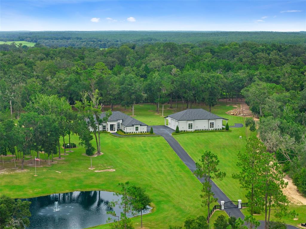 An aerial view shows a house and detached garage on a large, grassy, wooded lot — 1825 W OAK VALLEY COURT, HOMOSASSA, FL