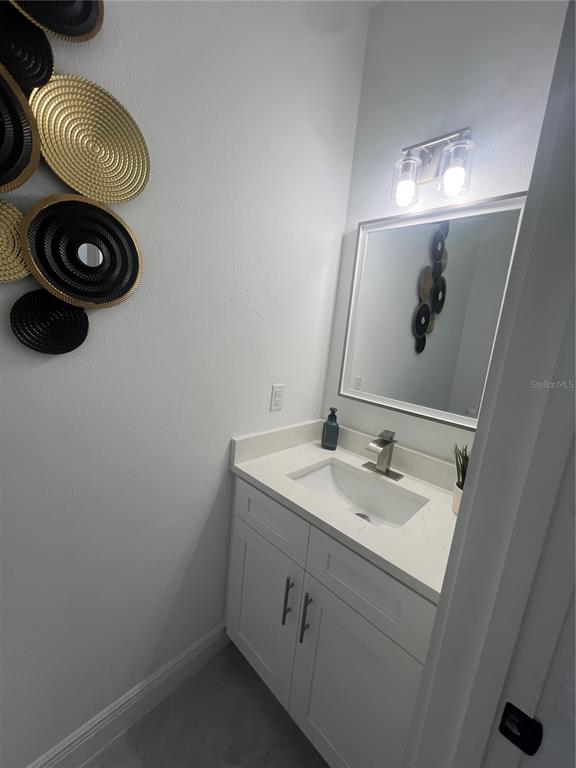 A small bathroom features a white vanity, a rectangular mirror, and decorative wall art — 6425 CURTIS STREET, ORLANDO, FL