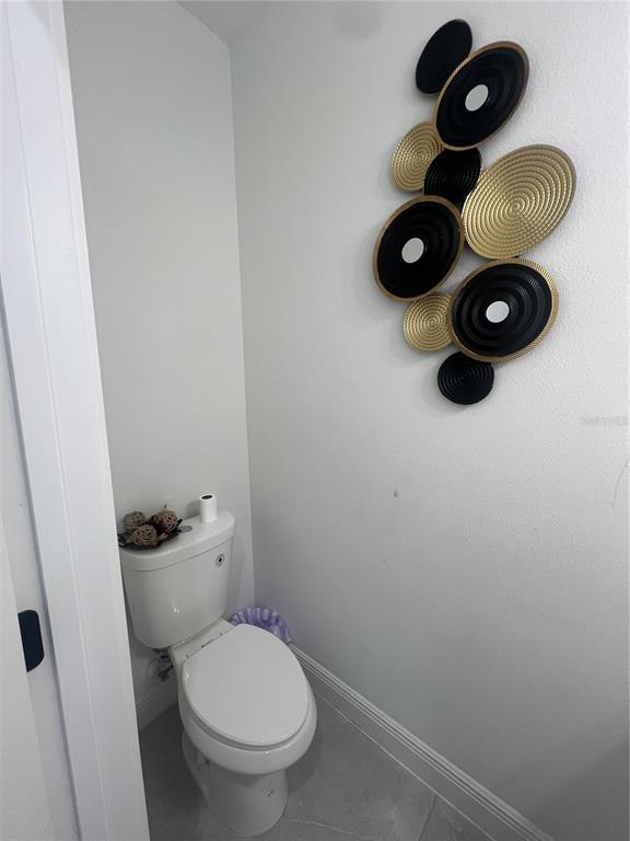 A small bathroom features a white toilet and a decorative wall sculpture with circular accents — 6425 CURTIS STREET, ORLANDO, FL