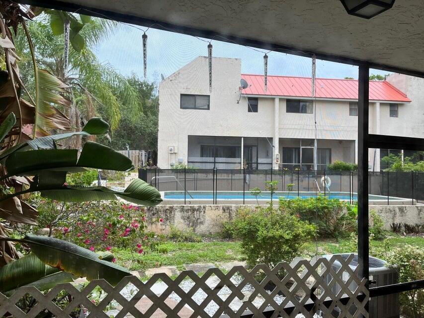 A view from a screened porch looking out toward a backyard swimming pool and house — 1679 NW 15th Vista, Boca Raton FL 33432, BOCA RATON, FL