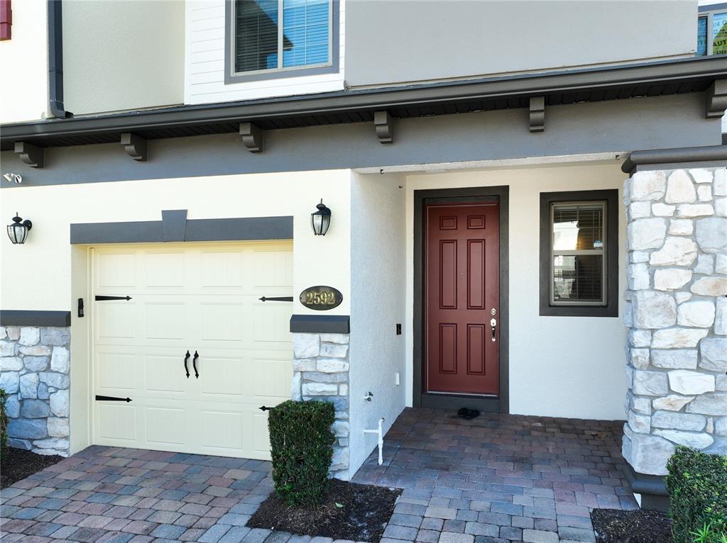 The exterior of a house features a garage, a red front door, and stone accents — 2592 ECON LANDING BOULEVARD, ORLANDO, FL