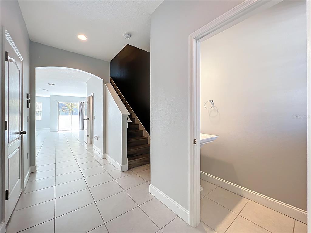 A tiled entryway features a staircase with dark wood steps and a small powder room — 2592 ECON LANDING BOULEVARD, ORLANDO, FL