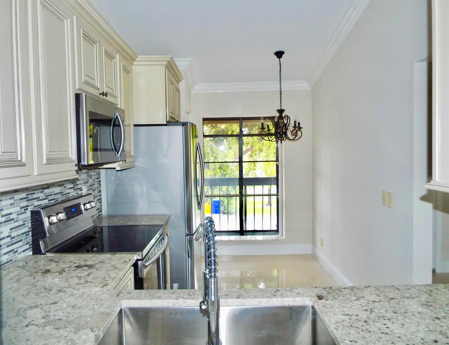 A kitchen features granite countertops, stainless steel appliances, light cabinetry, and a dining area window — 3350 Perimeter Drive # 1323, FL 33467, FL