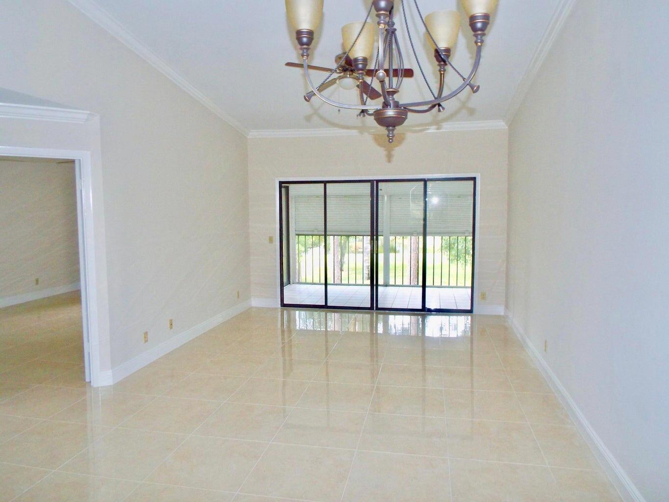 A dining room with light tile flooring, a chandelier, and sliding glass doors to a balcony — 3350 Perimeter Drive # 1323, FL 33467, FL