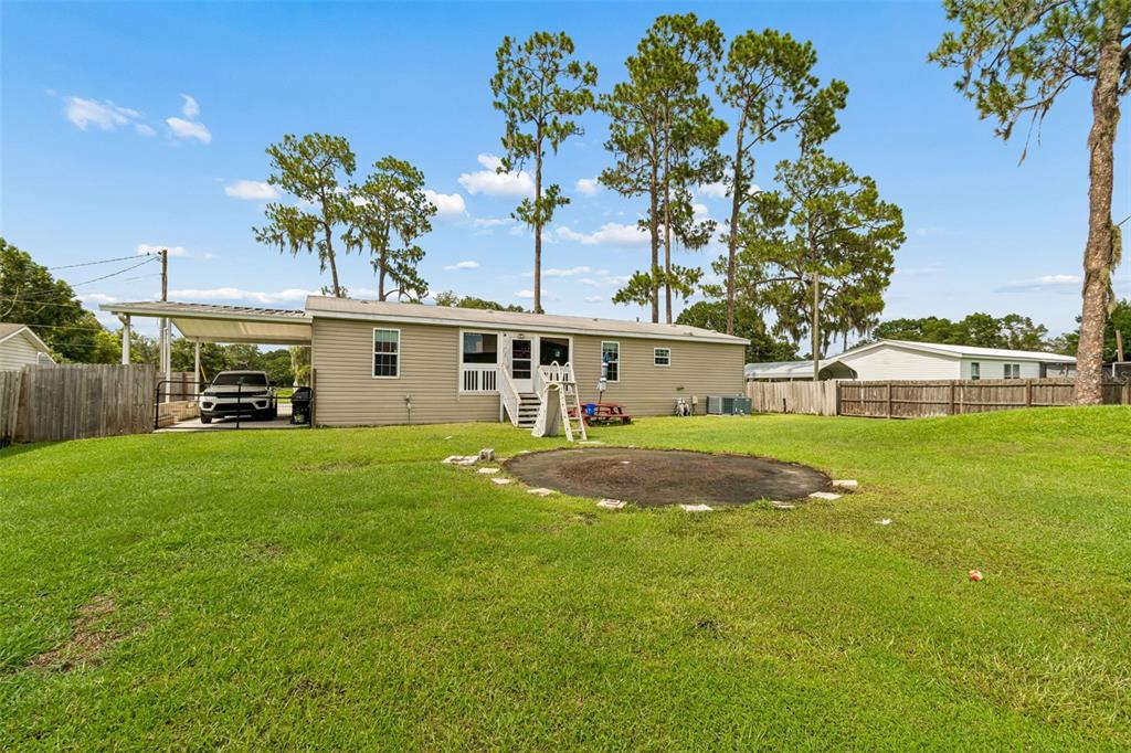 The exterior of a single-story house with a carport, a backyard, and a trampoline — 4917 HERNDON WAY, AUBURNDALE, FL